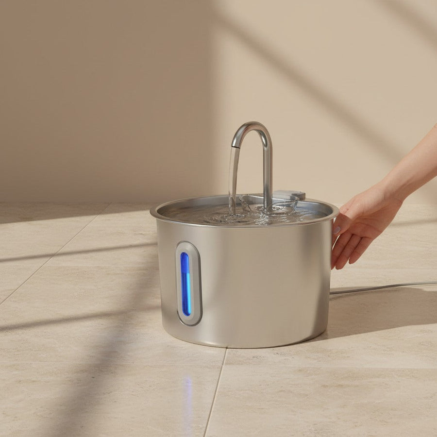 SafePaw™ stainless steel pet water fountain with a curved spout and blue LED water level indicator. Fresh water flows from the spout into the basin.